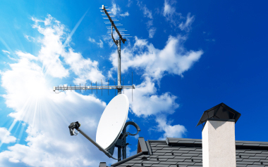 Satellite dish and TV antennas on the house roof with a beautiful blue sky